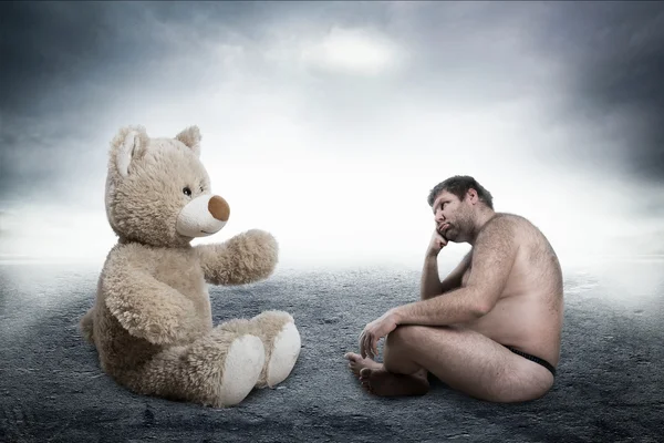 Homem olha para urso de brinquedo — Fotografia de Stock