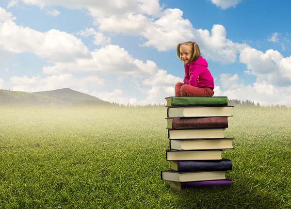 Meisje zit op de stapel boeken — Stockfoto