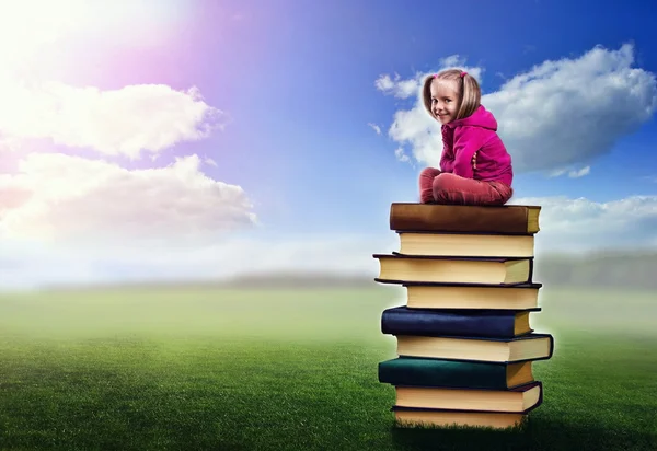 Mädchen sitzt auf Bücherstapel — Stockfoto