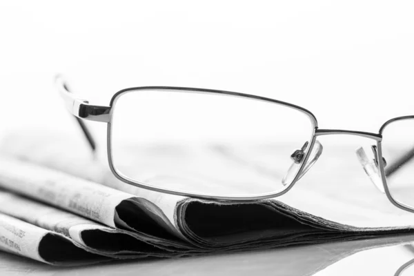 Brýle leží na noviny — Stock fotografie