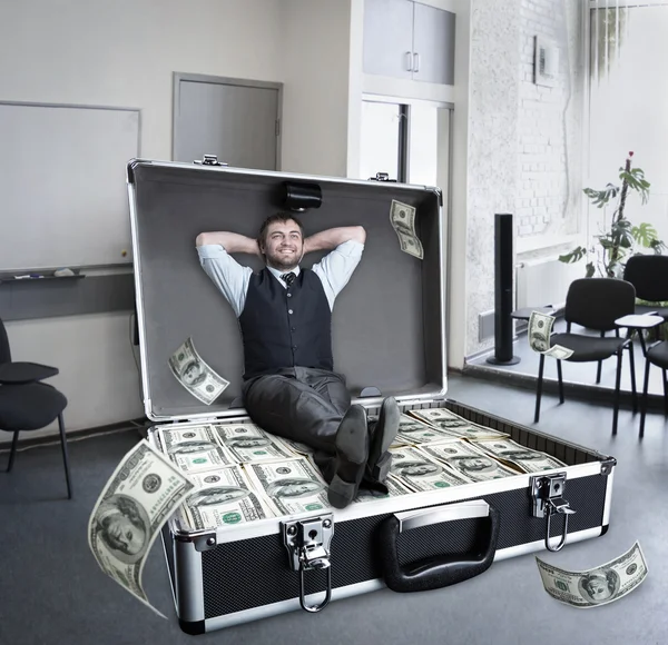 Happy businessman sits in the case full of dollars — Stock Photo, Image