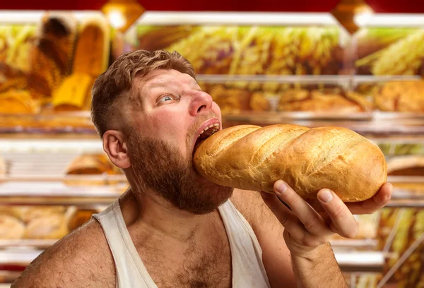 Man eating bread in the shop — Stock Photo, Image