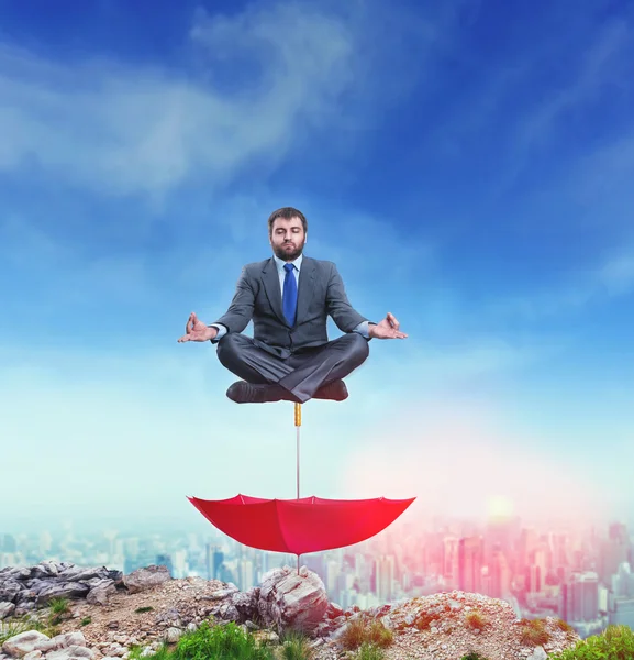 Empresário meditando em cima do guarda-chuva — Fotografia de Stock