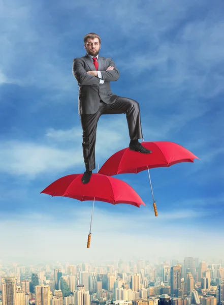 Confident businessman with umbrellas — Stock Photo, Image