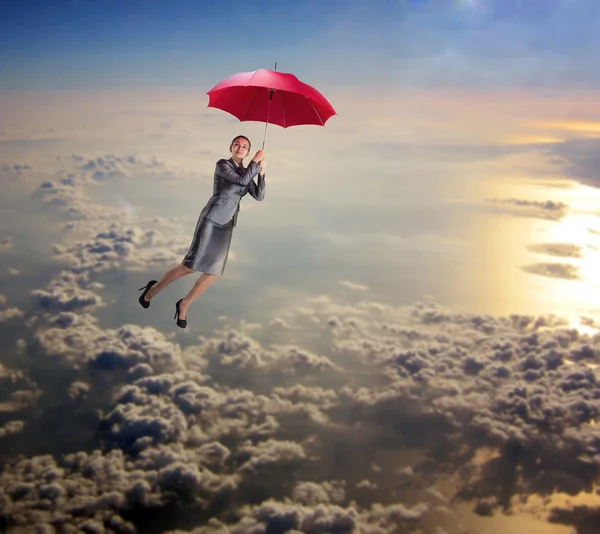 Dreamy woman flying in sky with umbrella — Stock Photo, Image
