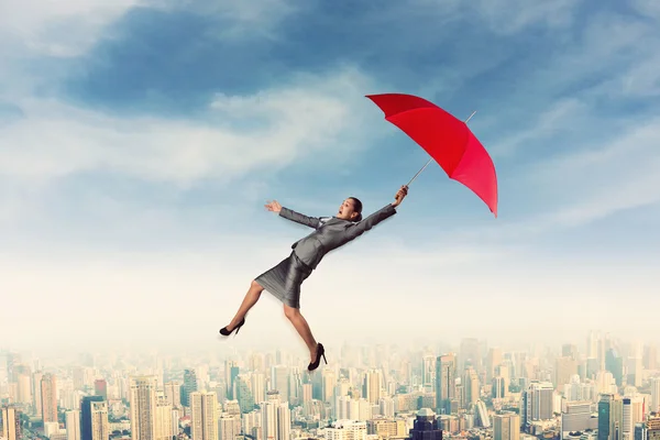 Frau fliegt mit Regenschirm in den Himmel — Stockfoto