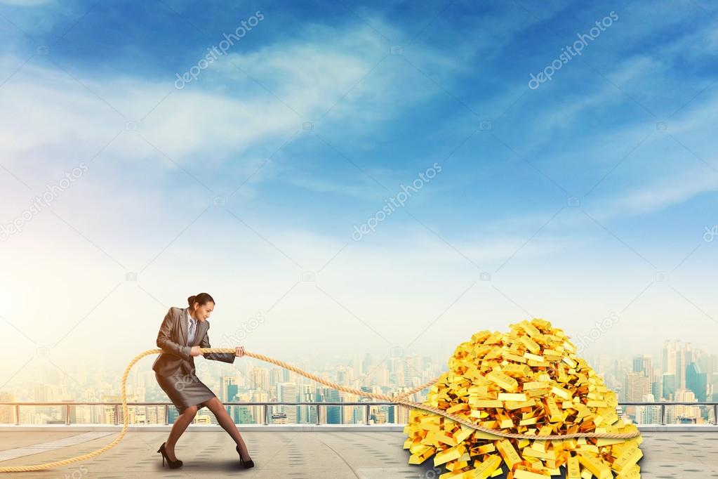Businesswoman pulls pile of gold bars