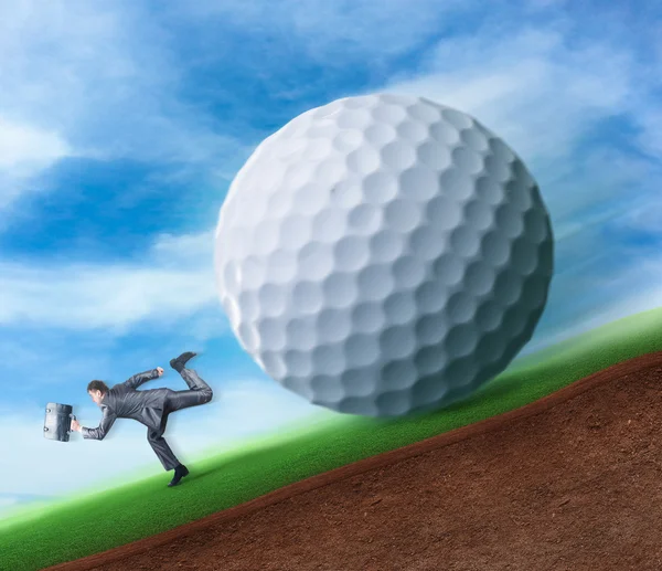 Businessman running from golf ball — Stock Photo, Image