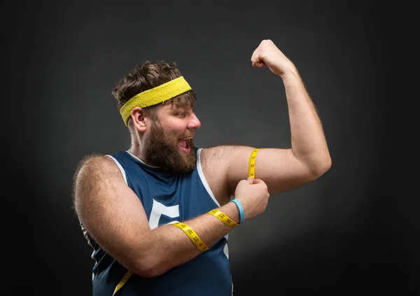 Fat man measuring  muscle — Stock Photo, Image