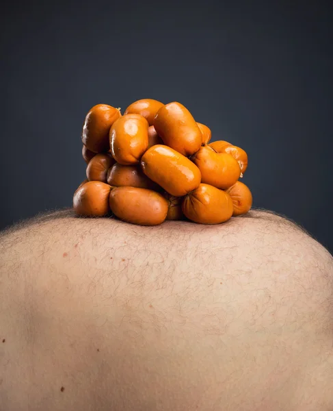 Würstchen auf fettem Männerbauch — Stockfoto
