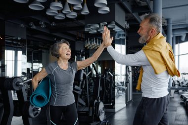 İki enerjik son sınıf öğrencisi modern bir spor salonunda çalışmalarını kutluyorlar, beşlik çakıyorlar ve birlikte gülümsüyorlar, zindelik ve canlılığı destekliyorlar..