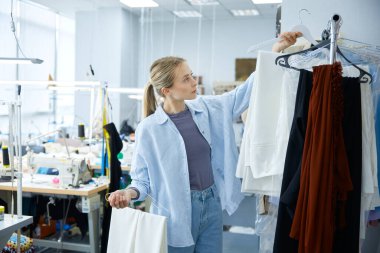 Bir tasarımcı, canlı ve yaratıcı bir moda stüdyosunun atmosferinde canlı kumaşları titizlikle sınıflandırıyor.