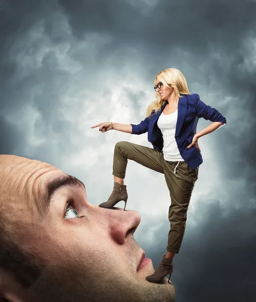 Woman standing on male face — Stock Photo, Image