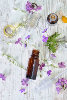 Masadaki küçük pembe çiçeklerin arasına dökülen yağ şişelerinin üst görüntüsü.