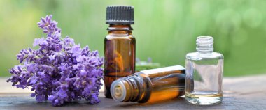 Ahşap bir masaya dizilmiş bir şişe gerekli yağ ve lavanta çiçeği.