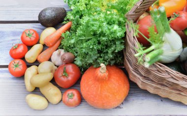 çeşitli ve renkli sebzeler bir sepetin yanındaki masaya konur.