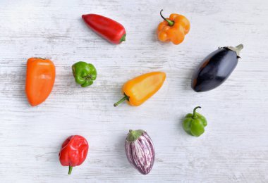 Küçük biberler ve beyaz masada patlıcanlar. 