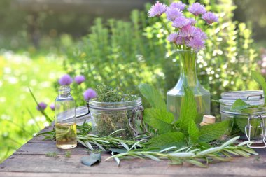 Cam kavanozlu aromatik bitki yaprağı ve bir bahçede masanın üzerinde duran yağ. 
