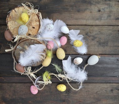 Ahşap arka planda beyaz tüylerle boyanmış dekoratif paskalya yumurtalarının üst görüntüsü 