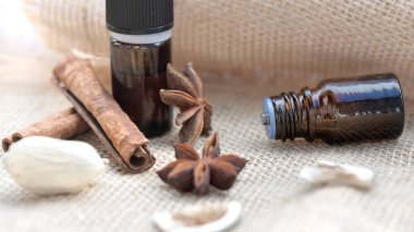 Doğal bir kumaş arka planında gerekli yağ ve tarçın çubuğu ve Badian şişeleri 