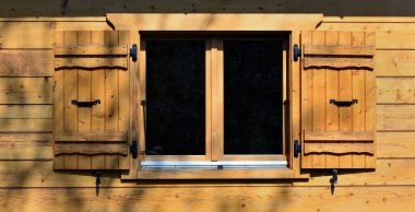 Geleneksel bir dağ evinin ahşap cephesinde pencere ve kepenkler. 