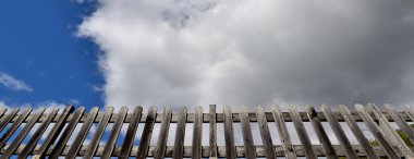 Gökyüzündeki bulutların altındaki ahşap çitin panoramik görüntüsü 