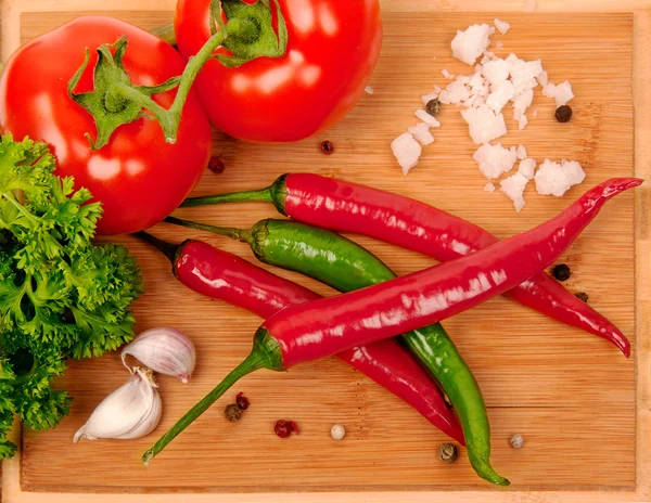 Red chili pepper, tomato and garlic on a wooden board — Stock Photo, Image