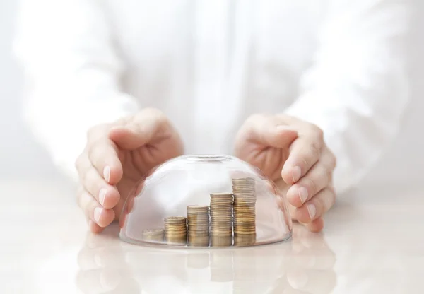 Rising coins protected under a glass dome and hands — Stock Photo, Image