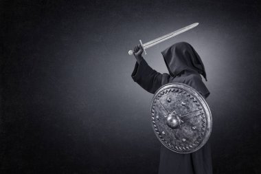 Karanlıkta kılıçlı ve yuvarlak kalkanlı hayalet figürü.