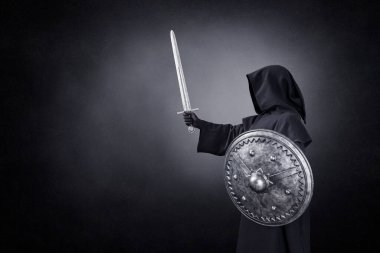Karanlıkta kılıçlı ve yuvarlak kalkanlı hayalet figürü.