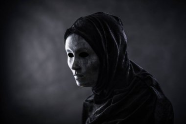 Karanlıkta kapüşonlu pelerinli korkunç bir figür.