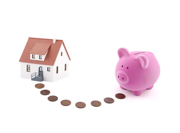 Saving for a house. Piggy bank with coins and house miniature. — Stock Photo, Image