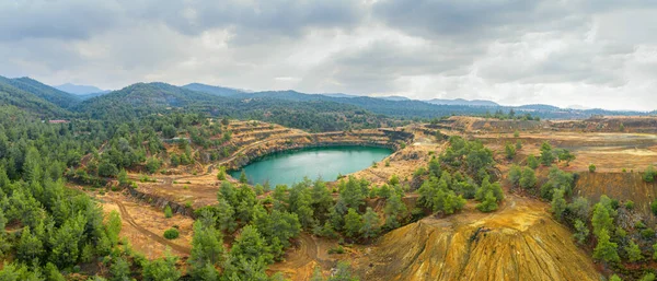 Restoration works in copper mining area with lake in open mine pit and spoil heaps covered with pine trees in Troodos mountains, Cyprus
