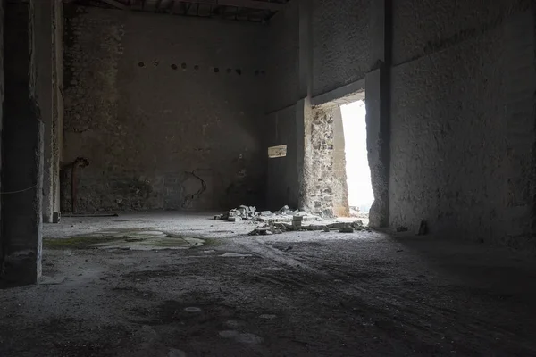 放棄された産業内部 コンクリート壁が割れた暗い空の倉庫 壊れたレンガと光がオープンドゥーを通って落ちる — ストック写真