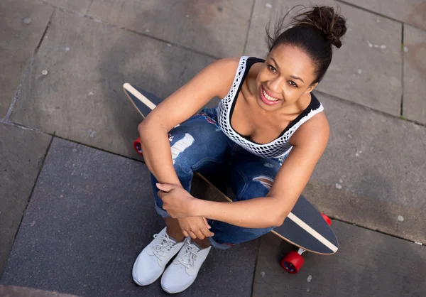Skateboard girl sitting on her board — Stock Photo, Image