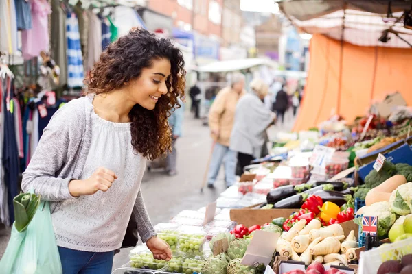 Jonge vrouw winkelen voor voedsel op een straatmarkt Stockfoto