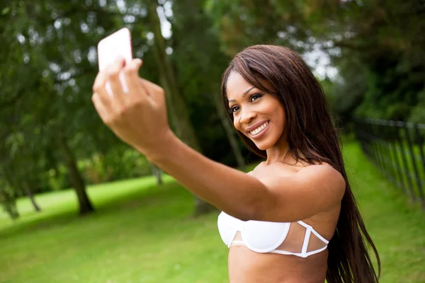 Junge Frau im Park macht ein Selfie im Bikini — Stockfoto