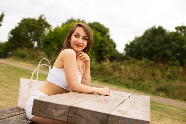 Ung kvinna sitter i parken — Stockfoto