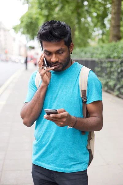 Людина тримає два телефони, роблячи дзвінок — стокове фото