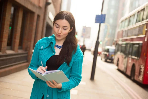 Mujer joven escribiendo en un cuaderno — Foto de Stock