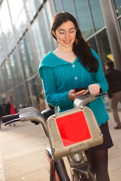 Fiatal nő, egy kerékpár bérlés, és a telefon — Stock Fotó