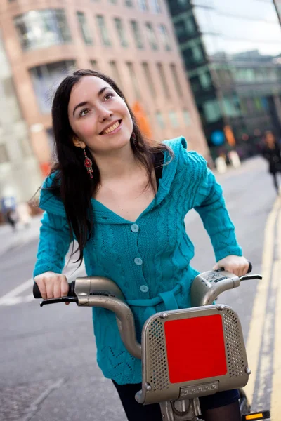 Mujer joven montando una bicicleta de alquiler — Foto de Stock