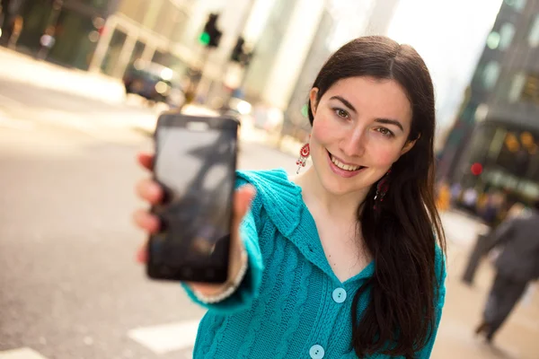 Junge Frau hält ihr Handy — Stockfoto