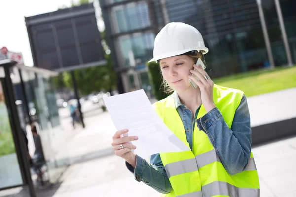 Trabajador de la construcción en el teléfono leyendo un documento —  Fotos de Stock