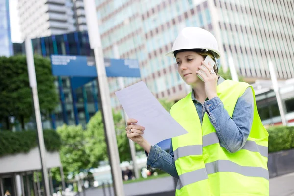 Pracownik budowlany w telefonie czytanie dokumentu — Zdjęcie stockowe