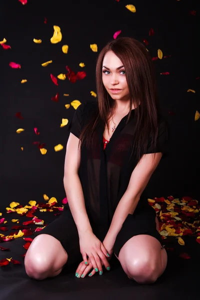 Beautiful young woman sitting under the falling petals