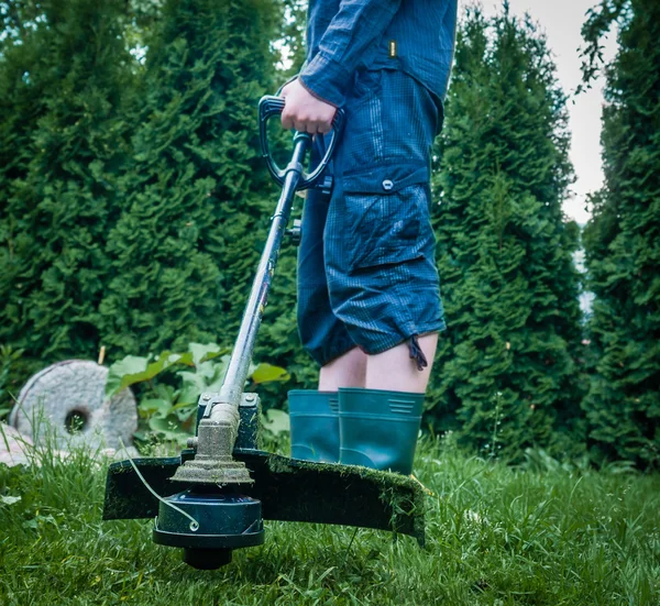 Killen med gräsklippare framför bakgården — Stockfoto