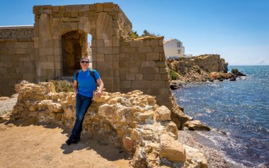 Olgun bir adam güneşli bir günde deniz kıyısında dinleniyor.