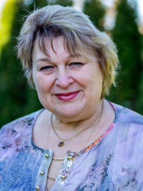 Neşeli, olgun bir kadın fotoğrafçıya gülümsedi. Şehir parkında dinleniyor... 