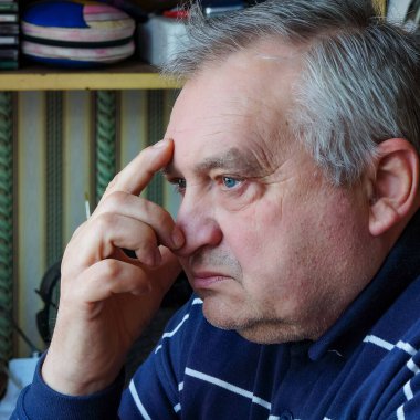 Mavi gömlekli yaşlı bir adamın yakın plan portresi..